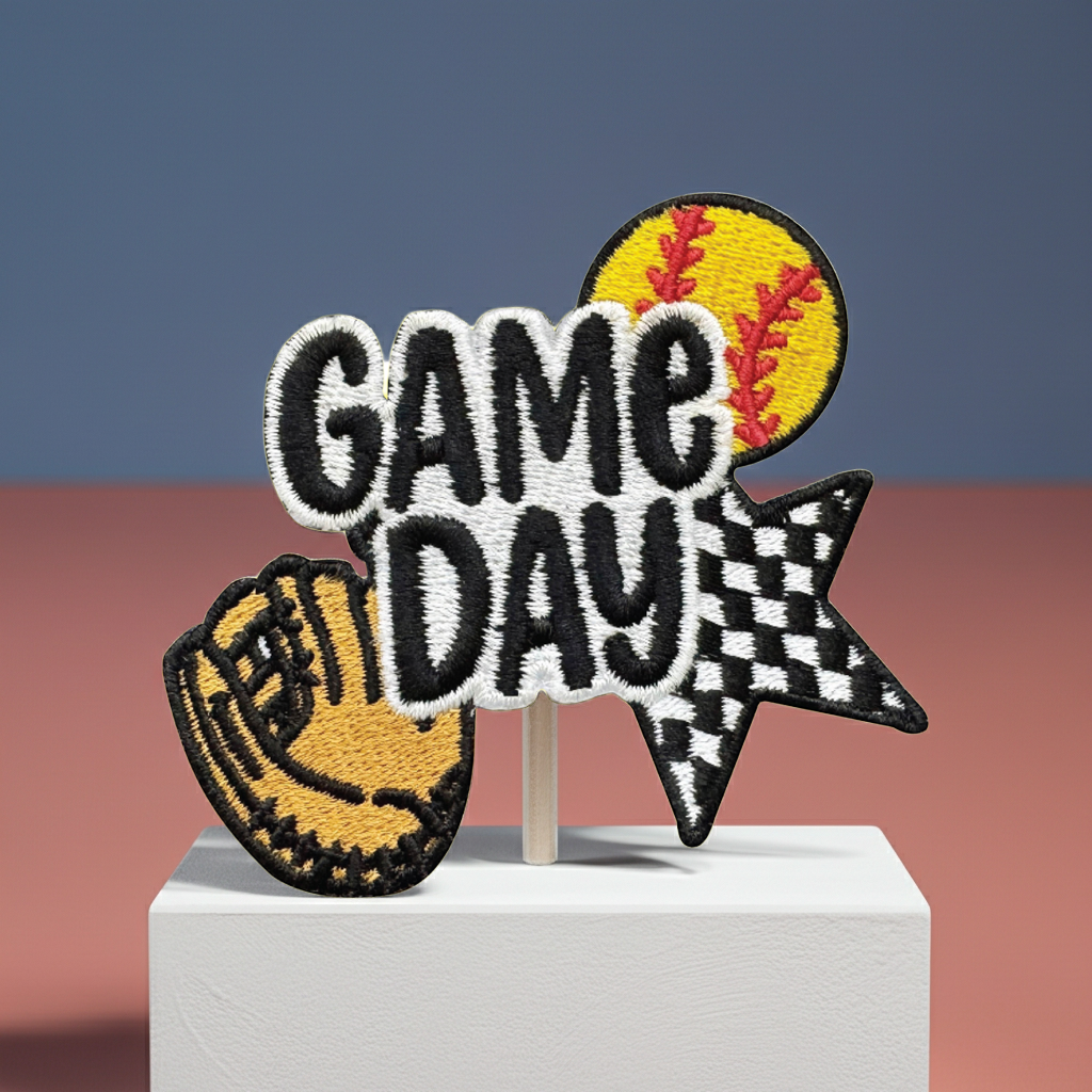 Embroidered patch with 'GAME DAY' text, softball, and baseball glove design on a stand against a gradient background.